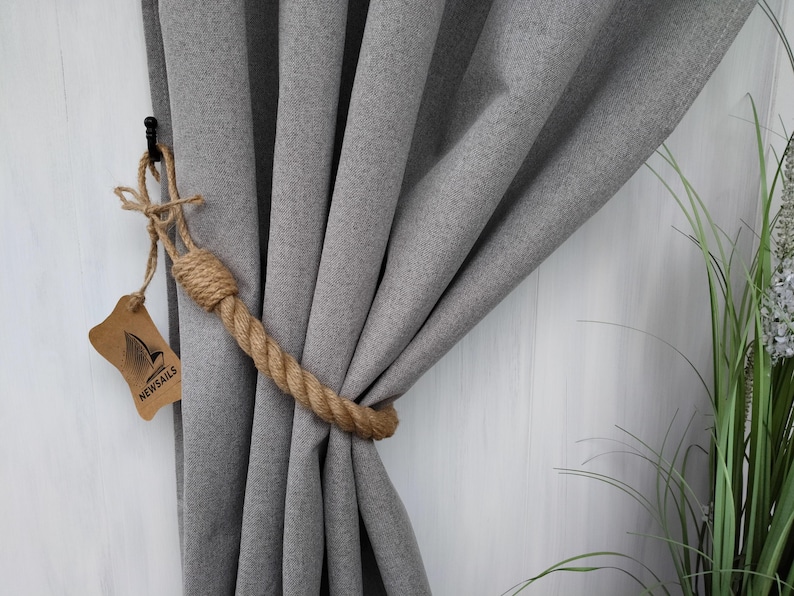 Pode incluir: Cortinas cinzas com um amarrador de corda. O amarrador &eacute; feito de corda natural e tem uma etiqueta castanha com o texto "NEWSAILS".