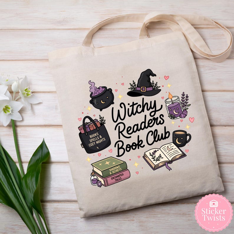 May include: Cream-colored tote bag featuring a whimsical design for a book club. The design includes a witch's hat, cauldron, books, a candle, and the text "Witchy Readers Book Club". The bag has a light beige strap.