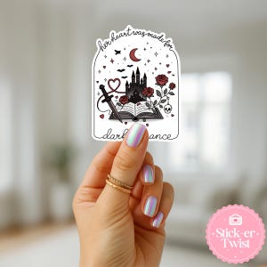 May include: A white sticker with a gothic castle, roses, a dagger, and the text "her heart was made for dark romance." The sticker has a black and red color scheme, with a crescent moon and stars.