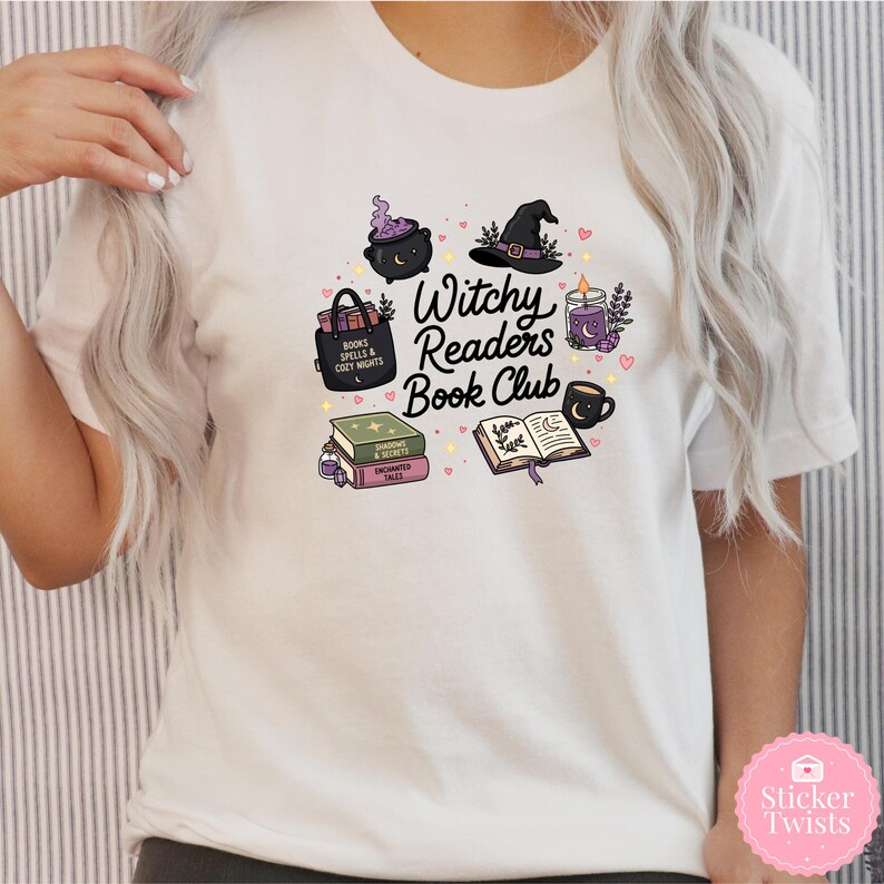 May include: White t-shirt featuring a colorful graphic design for a book club. The design includes a witch's hat, cauldron, books, a candle, and the text "Witchy Readers Book Club". The design is surrounded by small hearts.
