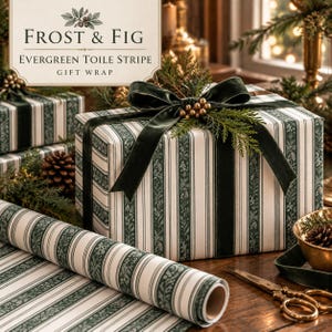 May include: A rectangular gift box wrapped in white and dark green toile stripe paper, tied with a dark green velvet ribbon and topped with a sprig of evergreen and gold berries. A matching roll of wrapping paper sits in the foreground.
