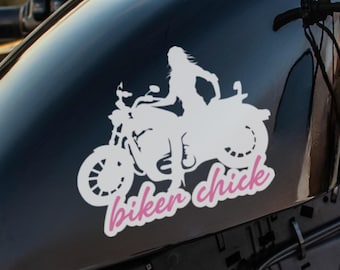 May include: A black motorcycle gas tank with a white graphic of a motorcycle and rider, with the words "biker chick" in pink script. The motorcycle has a chrome gas cap and black handlebars.