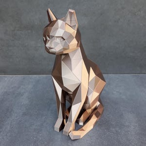 Könnte beinhalten: Eine geometrische Katzenfigur, die aus mehreren dreieckigen Facetten besteht. Die Skulptur weist eine metallische Farbpalette mit abwechselnden Bronze-, Kupfer- und Silbertönen auf, was ein facettiertes, polygonales Erscheinungsbild erzeugt.