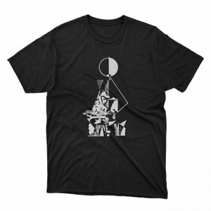 May include: Black t-shirt featuring a white graphic design. The design includes geometric shapes, a circle, and a figure playing an instrument. The graphic is a stylized, artistic representation.