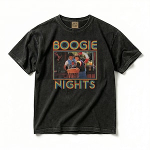 May include: A black short-sleeve t-shirt with a faded wash finish. The center features a rectangular graphic showing two people at a table with the text BOOGIE NIGHTS in a rainbow-colored font above and below the image. The shirt has a crew neck.