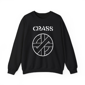 May include: Black crew neck sweatshirt with the word "CRASS" in white block letters above a white graphic. The graphic is a circle with a diagonal cross and arrows. The sweatshirt has long sleeves.