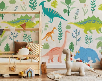 May include: A light brown wooden toddler bed with a white and green dinosaur themed wallpaper. The wallpaper features various dinosaurs, including a green stegosaurus, a blue brachiosaurus, a pink apatosaurus, and an orange velociraptor. The bed has a white and brown striped pillow and a white pom-pom pillow.
