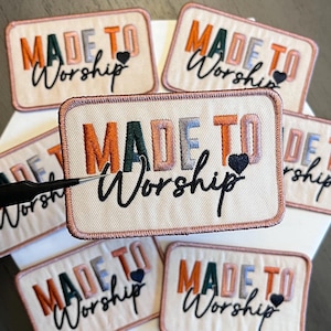 May include: Rectangular embroidered patches with the words "MADE TO Worship" in a mix of colors, including orange, green, and blue. Each patch has a small black heart. The patches are on a white surface.
