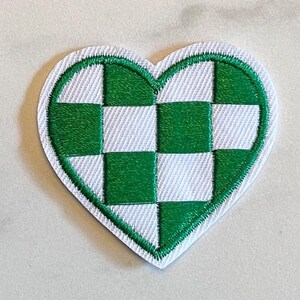May include: Embroidered heart-shaped patch featuring a green and white checkered pattern. The patch has a white border and is set against a light background. This patch is suitable for clothing or accessories.