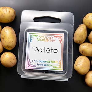 May include: A clear plastic package containing a soy wax melt scent sample labeled "Potato" with the Studio Pandemonia logo. Several raw potatoes are scattered around the package on a black surface.