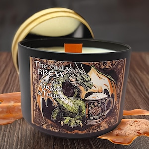May include: A black candle jar with a dragon and a beer mug design. The label reads "The Only Brew For the Brave & True".