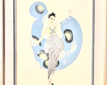 May include: An Art Deco print depicting a woman in a flowing gown with a blue, butterfly-shaped design. The artwork uses light blue, white, and black, framed in a light wood frame. The woman is wearing jewellery.