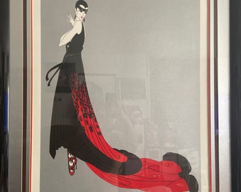 May include: An art print featuring a woman in a long black dress with a red train. She is wearing a black mask and has her hair pulled back. The print is framed in a black frame with a silver mount.