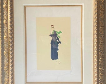 May include: A framed print of a woman in a black dress and green scarf. The print is on a cream background and is signed in the bottom right corner.