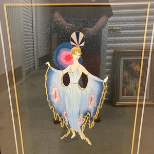 Könnte beinhalten: Ein gerahmter Kunstdruck mit einer Frau in einem blauen und weißen Kleid mit einem Federkopfschmuck. Der Hintergrund ist dunkelblau mit einem Sternenmuster.