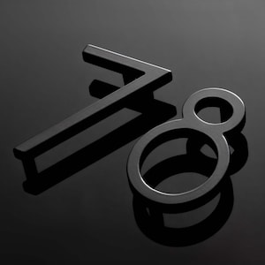 May include: A set of two three-dimensional house numbers, specifically the digits seven and eight, crafted from a smooth, matte black metal. The numbers are positioned at an angle, casting distinct shadows on the dark, reflective surface below.