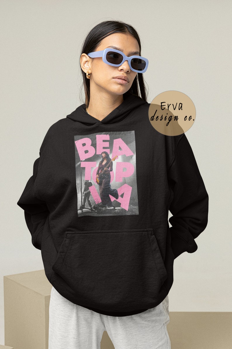 May include: Black hooded sweatshirt with a pink graphic print of a woman playing a guitar on stage. The graphic text reads "BEATopia".
