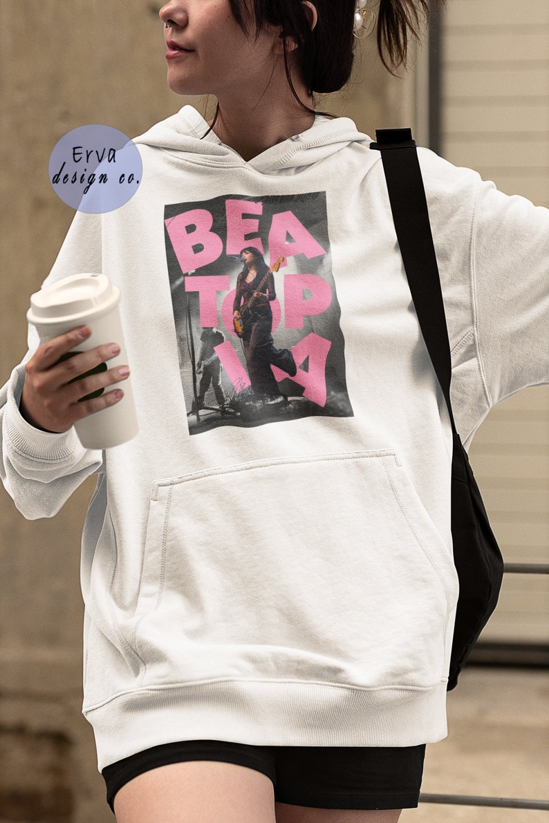 May include: White hoodie with a pink graphic print of a woman playing a guitar with the text "BEATOPIA".