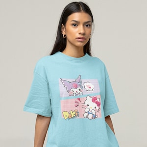 May include: A light blue t-shirt with a graphic print of Hello Kitty and a character from the Sanrio franchise. The graphic features the text "Doki Doki".