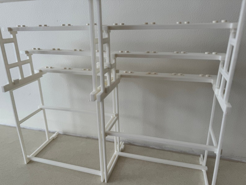 May include: White plastic shelf unit with multiple shelves. The shelves are made of a grid pattern and are designed to hold small items.