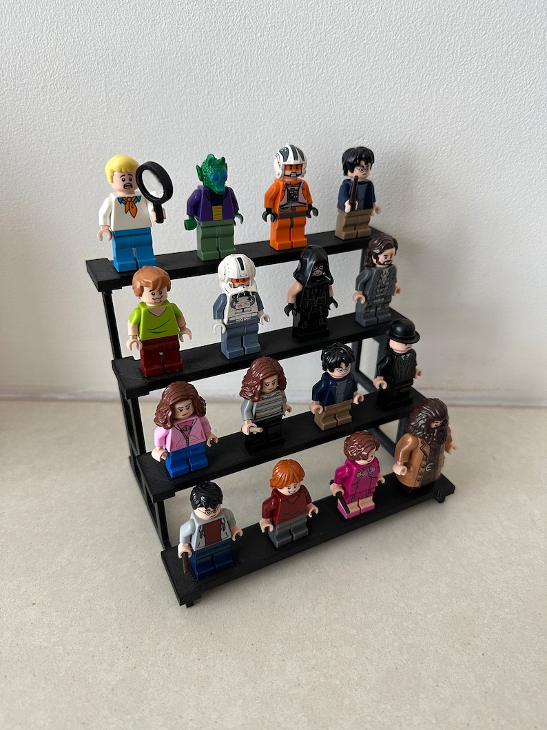 May include: A three-tiered black display stand with 16 miniature figurines. The figurines are made of plastic and feature characters from various popular franchises, including Harry Potter, Star Wars, and Scooby-Doo.