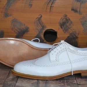 May include: White leather brogue shoes with a lace-up closure and a brown leather sole.