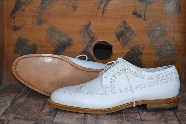 May include: White leather brogue shoes with a lace-up closure and a brown leather sole.
