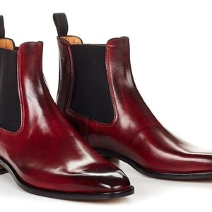 May include: A pair of burgundy leather Chelsea boots with elastic side panels and a pointed toe.