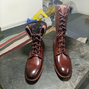 May include: A pair of brown leather boots with laces and a fur lining. The boots have a rounded toe and a low heel.