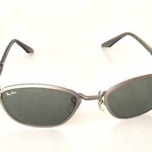 May include: Silver-toned Ray-Ban sunglasses with dark green lenses and a thin metal frame.