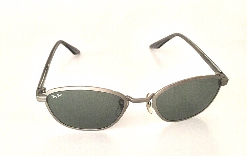 May include: Silver-toned Ray-Ban sunglasses with dark green lenses and a thin metal frame.