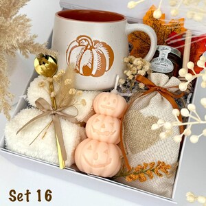 May include: A gift box labeled Set 16 containing a speckled ceramic mug with a pumpkin graphic, a stack of three pumpkin-shaped candles, a gold spoon, a small jar of honey, a wooden honey dipper, and a burlap pouch with a heart design.