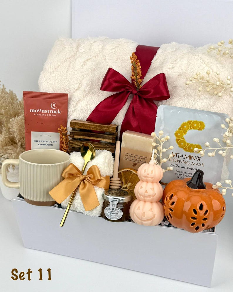 May include: A gift set containing a cream-coloured ribbed mug, a Moonstruck milk chocolate cinnamon bar, a gold spoon, a white fuzzy cloth, a wooden honey dipper, a jar of honey, oatmeal soap, a Vitamin C mask, and a pumpkin-shaped candle.