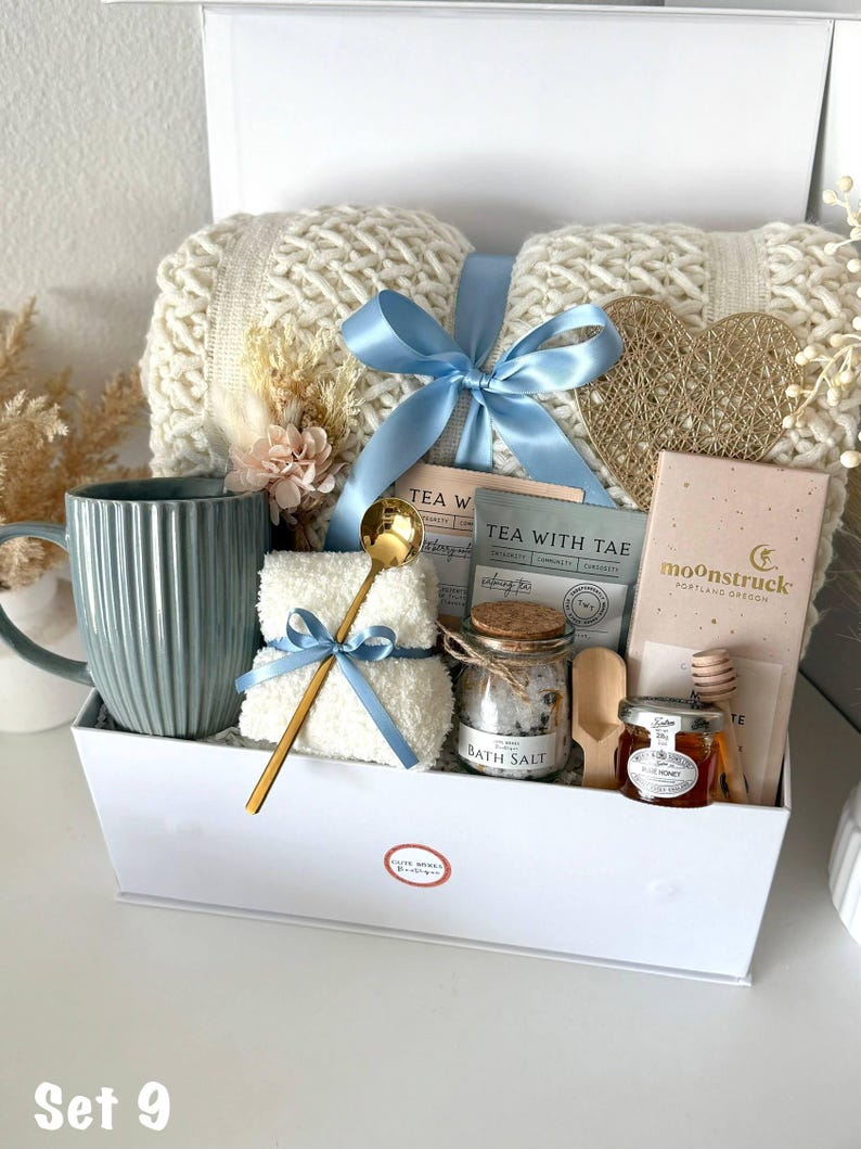 Puede incluir: Una caja de regalo blanca llena de art&iacute;culos de cuidado personal. Incluye una manta de punto color crema atada con una cinta azul claro, una taza azul, sales de ba&ntilde;o, t&eacute;, miel y una cuchara dorada. Tambi&eacute;n se incluye un coraz&oacute;n dorado decorativo.