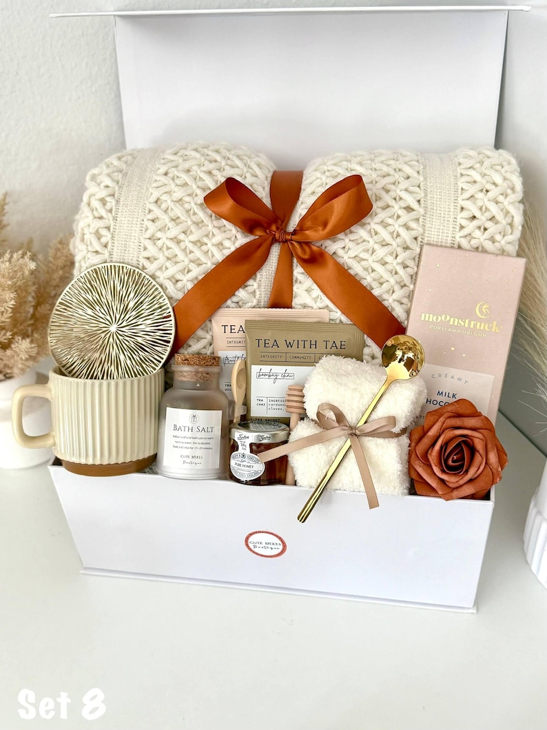 Puede incluir: Una caja de regalo blanca llena de una manta de punto color crema atada con una cinta color &oacute;xido. Tambi&eacute;n contiene una taza, sal de ba&ntilde;o, miel, un osito de peluche, una tableta de chocolate, una cuchara dorada, un posavasos y una rosa.