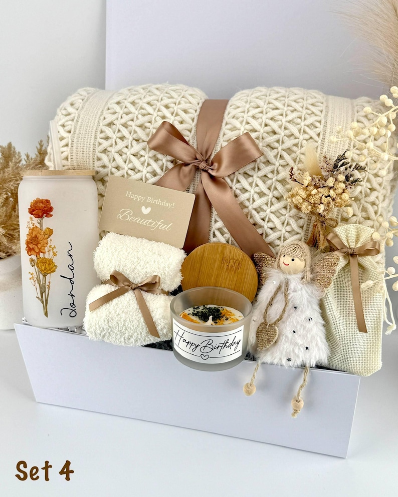 May include: A gift set containing a cream-colored knit blanket tied with a brown ribbon, a frosted glass tumbler with floral art and the name Jordan, a small candle with a bamboo lid, a plush angel ornament, and a small pouch, labeled Set 4.