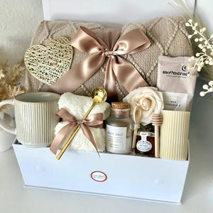 Puede incluir: Caja de regalo con art&iacute;culos de cuidado personal. Incluye una manta beige, una taza, sales de ba&ntilde;o, una toalla, miel, una vela y un coraz&oacute;n decorativo. La caja est&aacute; atada con una cinta de raso.