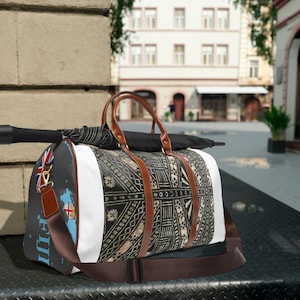 Könnte beinhalten: Eine schwarze und braune Reisetasche mit weißem Hintergrund und einem gemusterten Design. Die Tasche hat einen braunen Ledergriff und einen braunen Riemen. Die Tasche hat das Wort "FIJI" auf der Seite aufgedruckt.