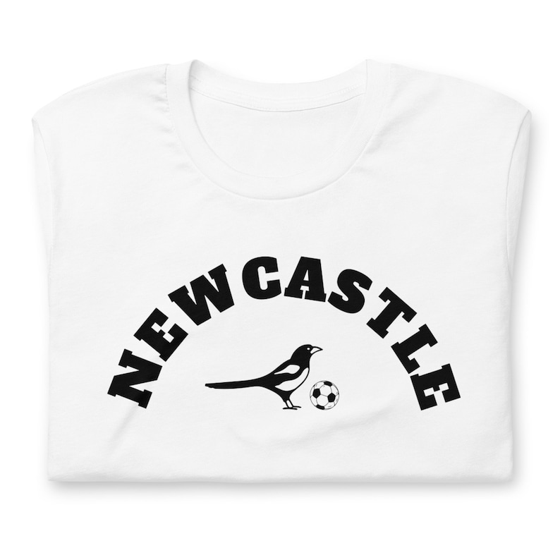 May include: White t-shirt with black text that reads "NEWCASTLE" in an arc shape. A black and white magpie with a football is centered below the text.