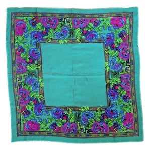 May include: A square scarf in a vibrant teal color featuring a wide border decorated with a dense floral pattern of bright pink and deep blue roses surrounded by green leaves. The central area of the scarf is a solid, plain teal fabric.