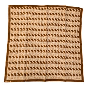 May include: A brown and cream silk scarf with a repeating pattern of chairs and tables. The scarf has a brown border and the text "Usac" is printed in the bottom left corner.