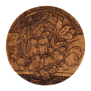 May include: A wooden round plate with a burnt design of a basket of peaches and leaves.