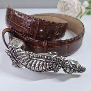 May include: A set of three ceramic vases in varying heights and shapes. The vases are glazed in a matte, earthy green color. The tallest vase is approximately 10 inches high.