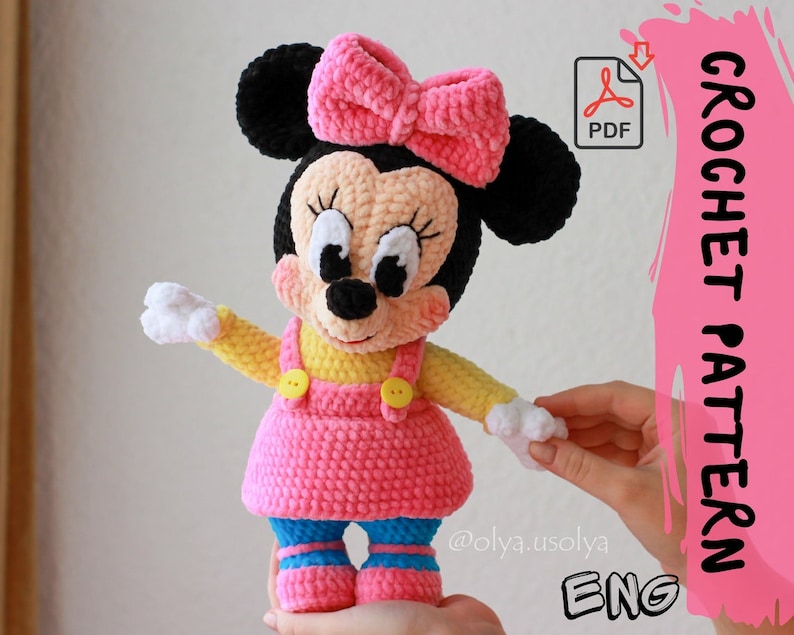 May include: Crochet pattern for a pink and yellow Minnie Mouse amigurumi doll. The pattern is available in PDF format and includes instructions in English. The doll has a black nose, white eyes, and a pink bow.