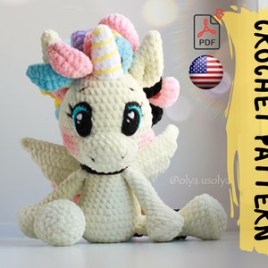 May include: Crochet pattern for a white unicorn amigurumi toy with a rainbow mane and horn. The pattern is available in PDF format and is written in US English. The pattern is by @olya_usolya.