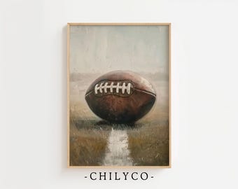 May include: A framed print of a vintage football. The brown leather ball with white laces rests on a grassy field, with a light-colored reflection. The artwork has a muted color palette and a soft, painterly style.