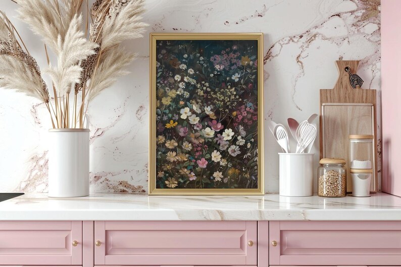 May include: A framed print of a floral arrangement featuring a variety of flowers in shades of pink, purple, and white. The flowers are arranged in a dense cluster, creating a vibrant and colourful display. The print is framed in a gold frame and is hanging on a white marble wall.