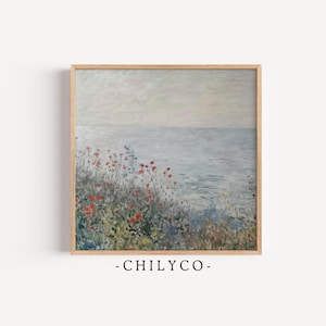 May include: A framed print of a coastal landscape painting. The artwork depicts a serene seascape with a cloudy sky and a foreground of wildflowers in shades of red, green, and blue. The frame is made of light-colored wood. The text "-CHILYCO-" is at the bottom.