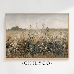 Puede incluir: Una pintura de un campo de flores silvestres en tonos marrones, verdes y blancos. El cielo es de un gris suave con un toque de azul. La pintura está enmarcada en un marco de madera claro.