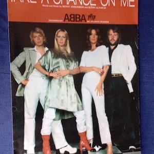 Könnte beinhalten: Notenblatt-Cover für ABBA's "Take a Chance on Me". Das Cover zeigt ein Foto der Bandmitglieder. Der Titel steht in großen, fetten Buchstaben oben, darunter der Name der Band und das Label.